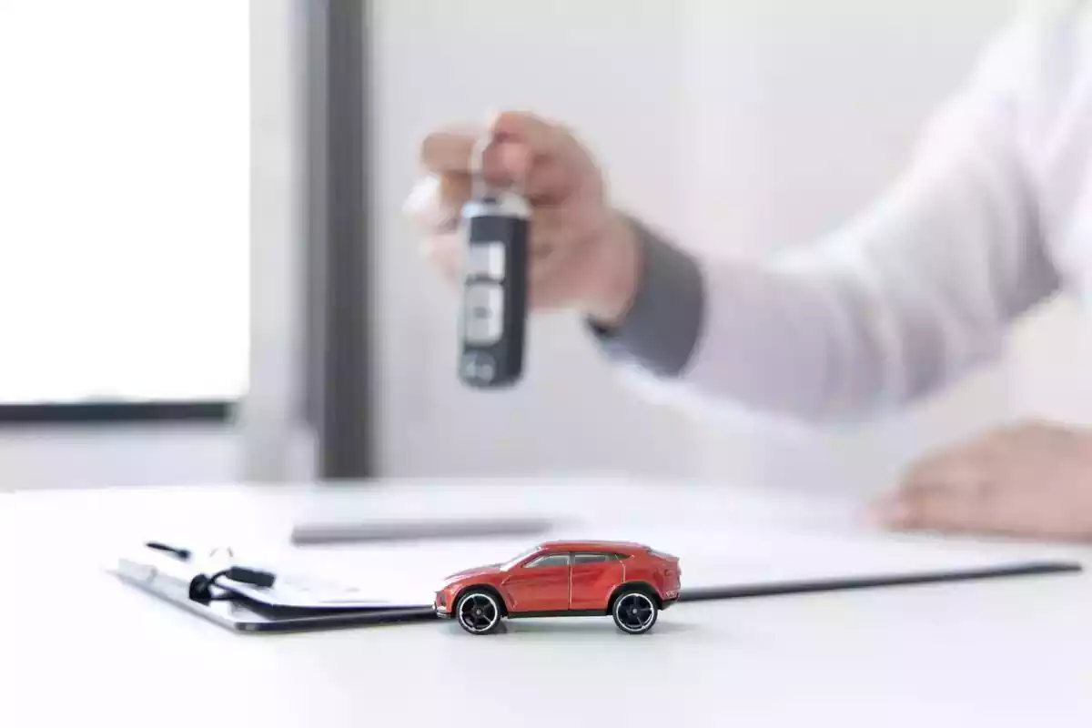 Foto d'una persona entregant unes claus de cotxe i un cotxe de joguina vermell