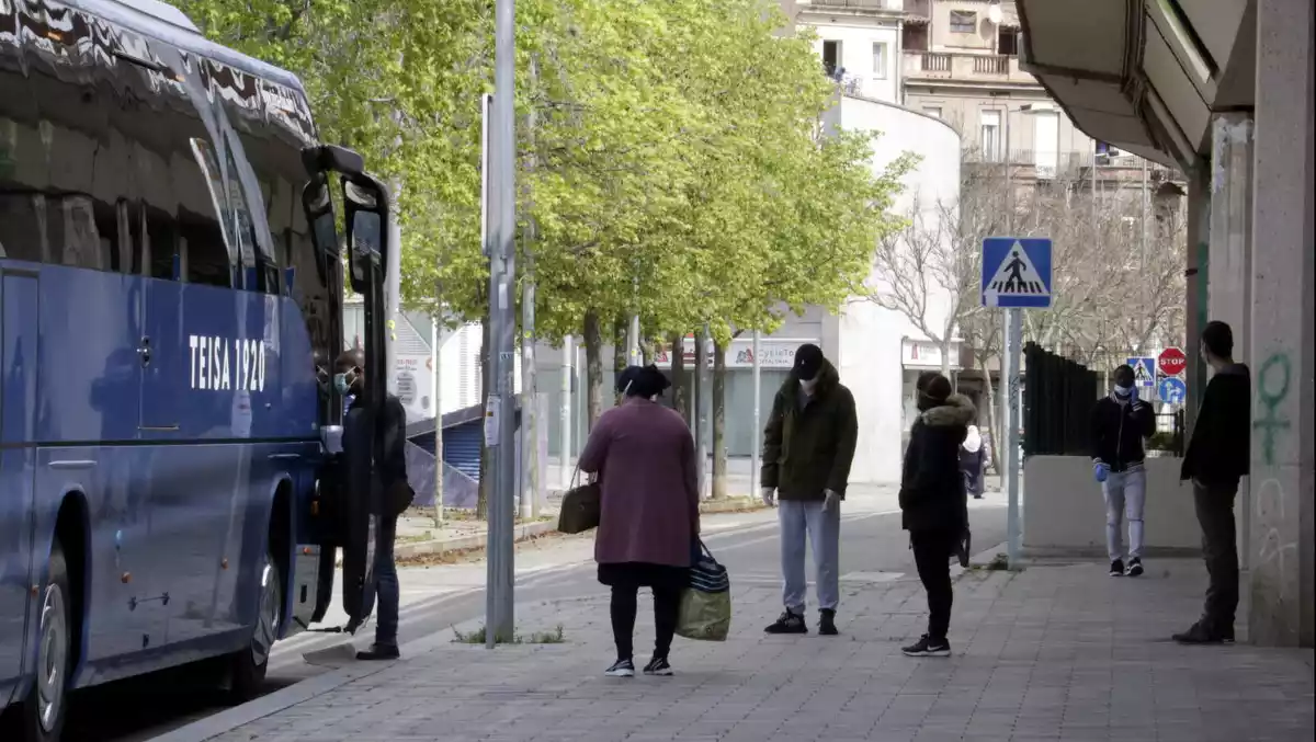 Imatge d'uns ciutadans de Girona respectant la distància de seguretat a la cua per pujar al bus