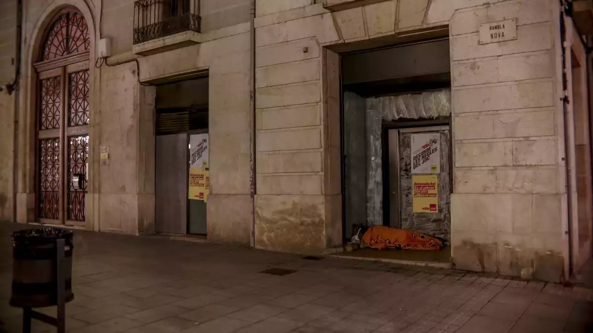 Un sensesostre passa la nit a un portal d'un local buit ubicat a la Rambla Nova de Tarragona.