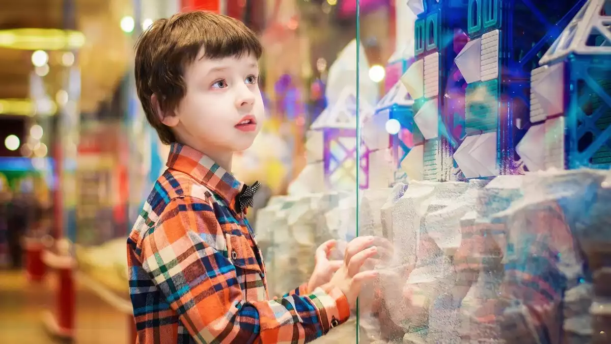 Un nen mira l'aparador d'una botiga de joguines