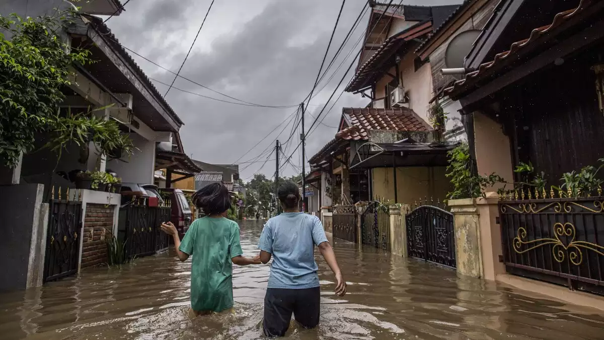 Dues dones caminen per un carrer inundat després d'una forta pluja a Jakarta i voltants.