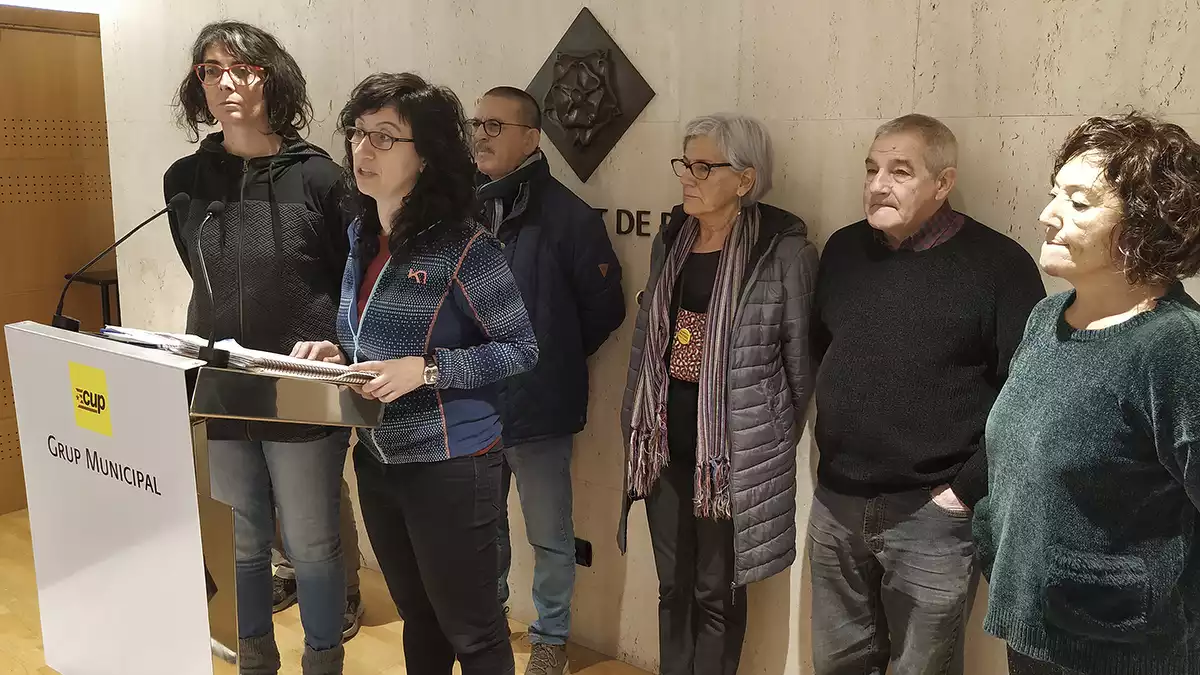 Marta Llorens i Mònica Pàmies, dempeus al faristol de la sala de premsa amb quatre membres de la CUP la CUP al darrere