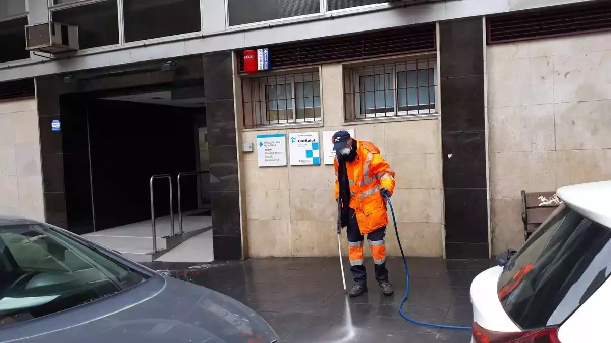 Un operari neteja amb aigua i desinfectant la vorera davant del CAP Jaume I de Tarragona