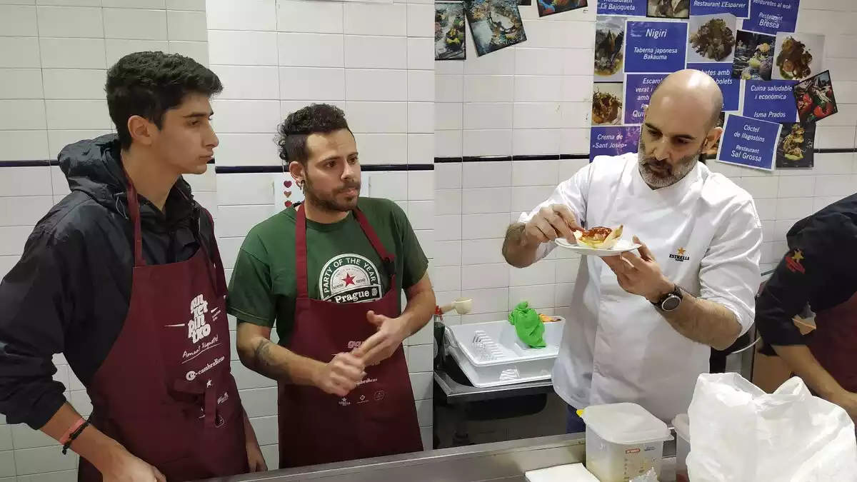 Dos dels cuiners participants mostren la seva proposta al que els ha d'aconsellar, que se la mira atentament