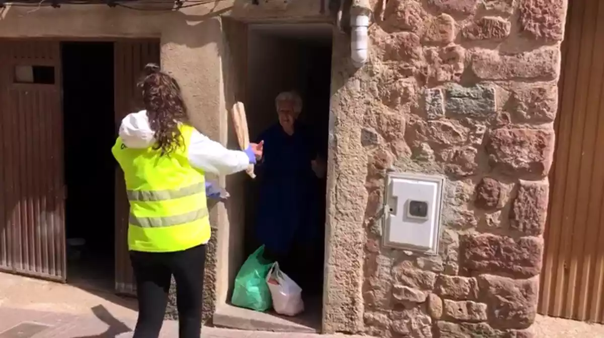 Imatge d'una voluntària portant la compra a una veïna confinada de Prades