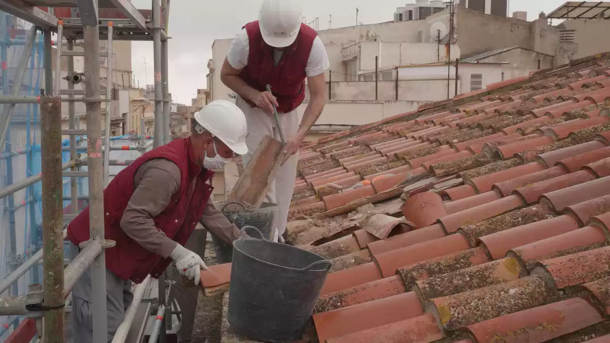 Dos operaris treballen en una teulada