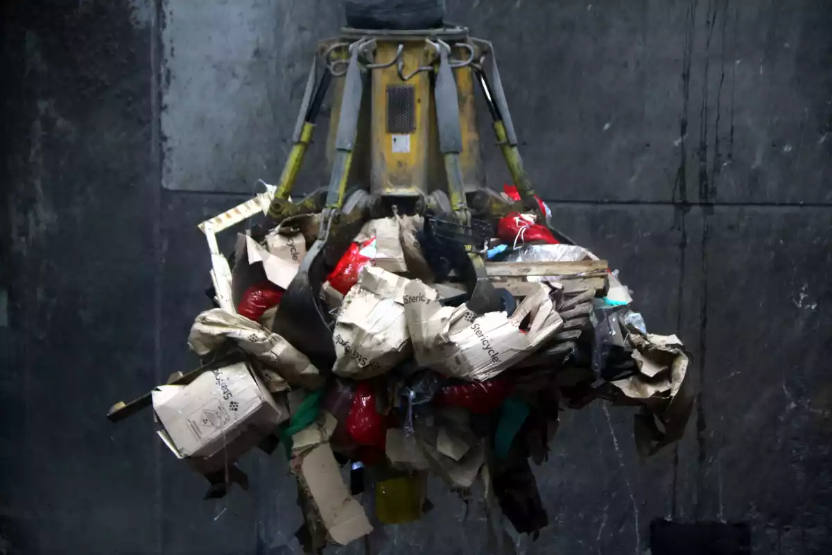 Pla tancat del ganxo d'una grua elevant diverses bosses de residus sanitaris per introduir-les al forn de la incineradora de Tarragona