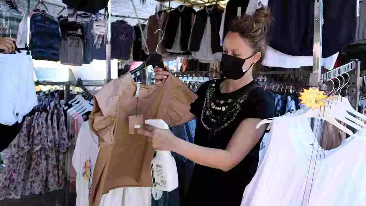 Pla obert d'una paradista desinfectant una peça de roba en una de les parades del mercat de Bonavista que ha reobert després de tres mesos d'inactivitat. Imatge de 21 de juny del 2020