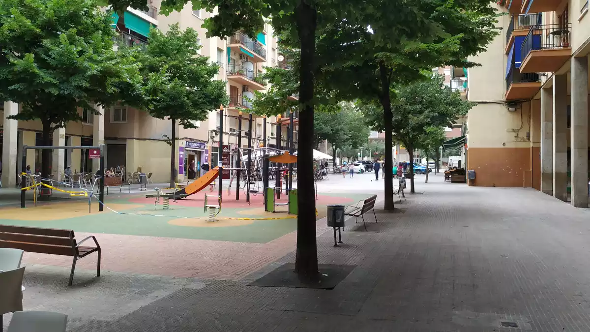Part central del carrer de la Sardana de Reus, amb un parc infantil al mig envoltat de bancs