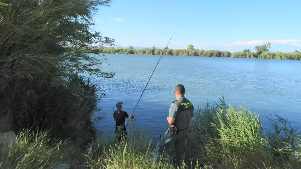 Imatge d'un agent de la Guàrdia Civil, a punt d'identificar un pescador al riu Ebre