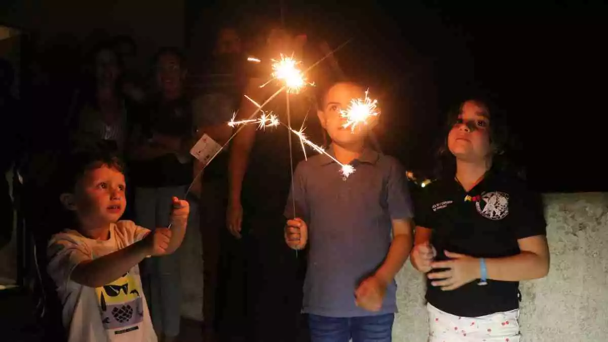 Pla mitjà de tres nens de l'Espluga de Francolí jugant amb unes bengales enceses durant la revetlla de Sant Joan, el 23 de juny del 2020.