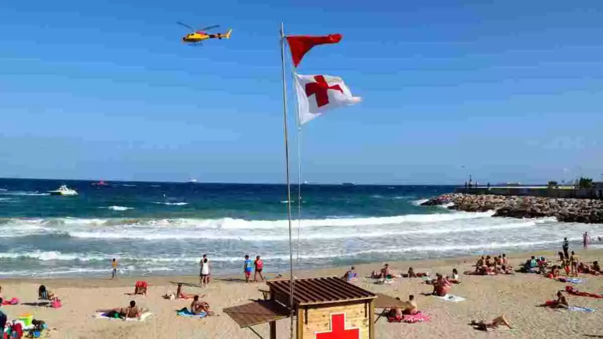 Imatge d'una platja amb bandera vermella i un helicòpter del SEM