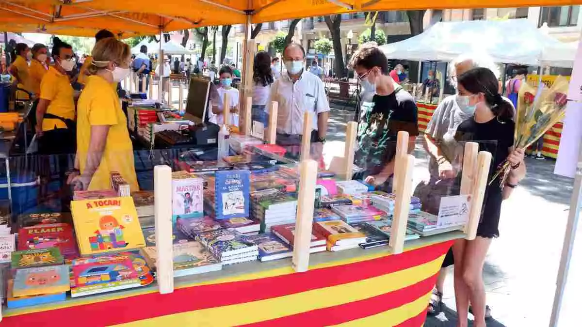 Una parada de llibres a la Rambla Nova de Tarragona amb diversos clients