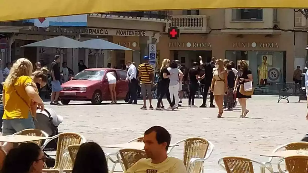 Un cotxe aturat a la plaça del Mercadal amb un grup de persones al seu voltant