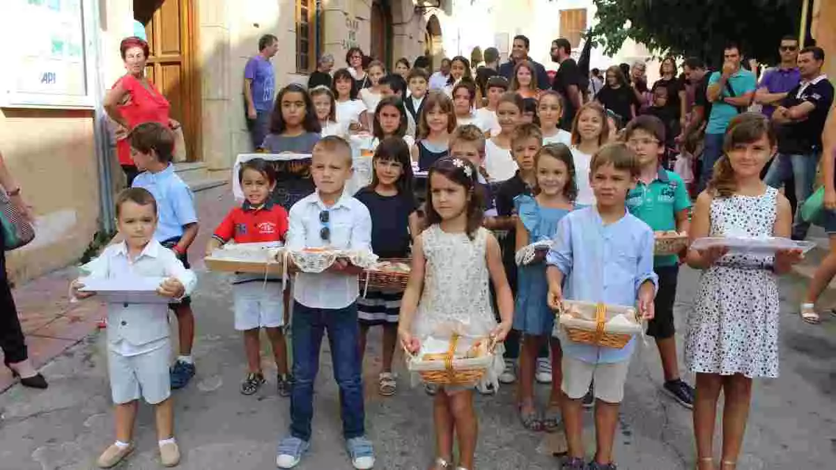 Els nens i nenes durant la tradicional Processó amb les safates guarnides amb les coques del Pa Beneit pels carrers del nucli històric de Creixell