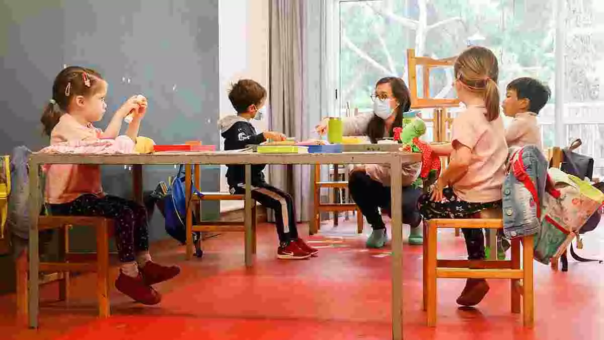 Imatge de diversos alumnes d'infantil fent activitats en una aula amb la professora.