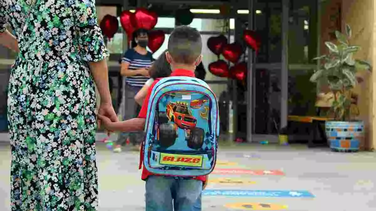 Imatge d'un nen arribant a l'escola de la mà de la seva mare