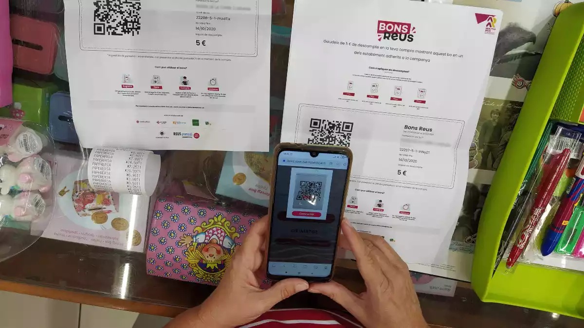 Un mòbil escanejant el paper dels Bons Reus amb un codi QR