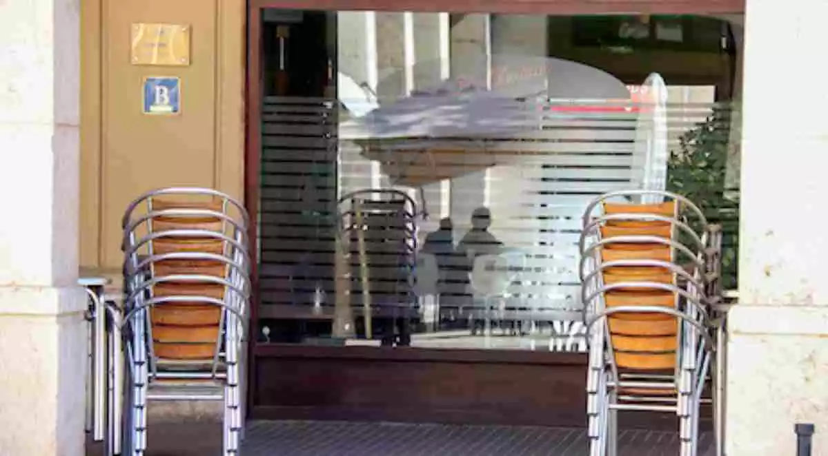 Pla general de la façana i les cadires d'un bar tancat al centre de Tortosa
