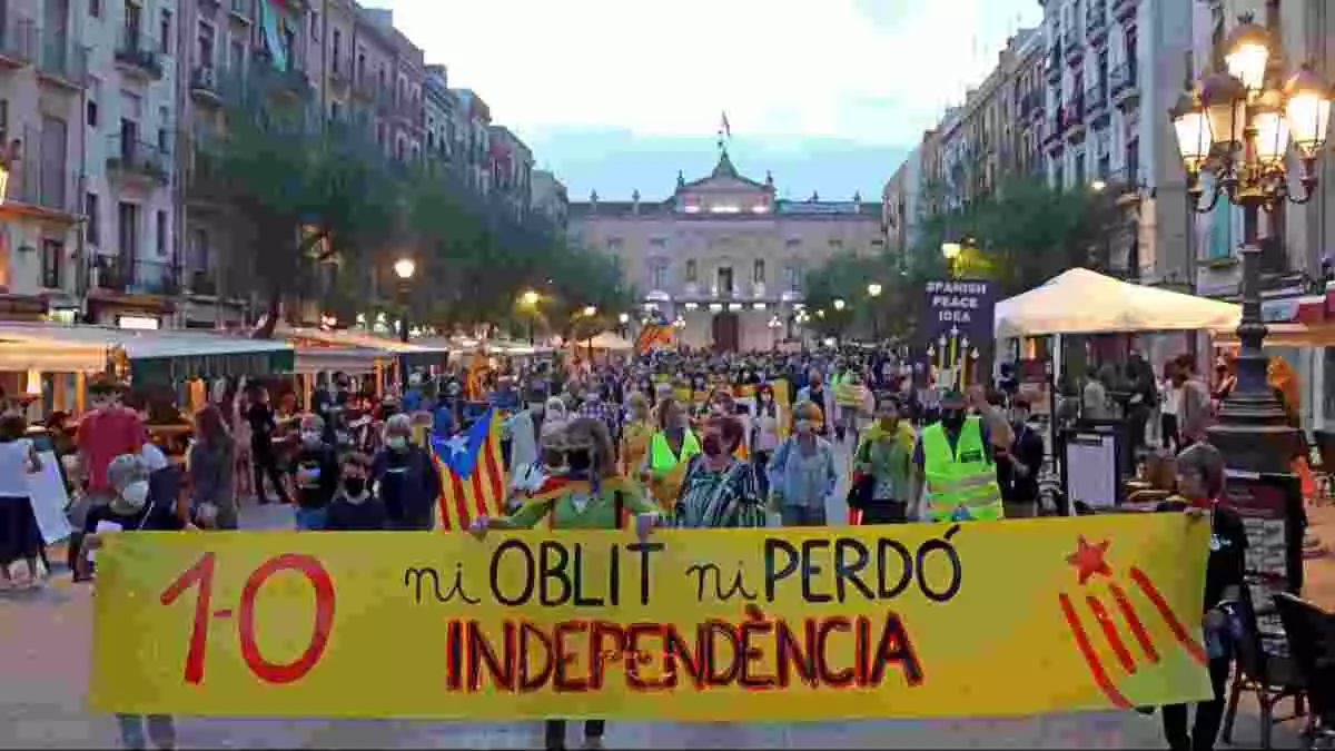 Pla general de les persones concentrades a la plaça de la Font de Tarragona iniciant la manifestació amb una pancarta amb el lema '1-O, Ni oblit ni perdó, Independència'.