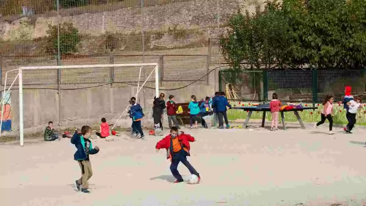 Pla obert de nens jugant a futbol durant l'hora d'esbarjo al pati de l'escola Cor de Roure de Santa Coloma de Queralt (Conca de Barberà)