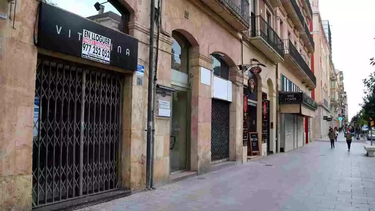 Pla obert d'una zona de la Rambla Nova de Tarragona on s'hi aprecien tres locals comercials buits