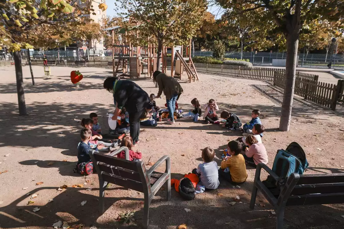 Una rotllana de nens i nenes esmorzant en un parc infantil