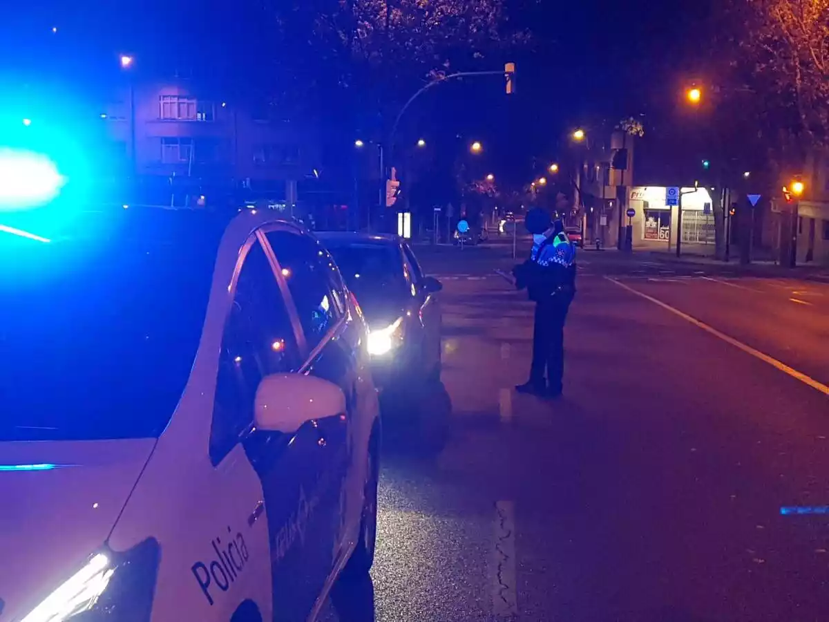En primer pla, un cotxe de la Guàrdia Urbana de Reus; al darrere un cotxe particular i, al costat, un agent posant una multa