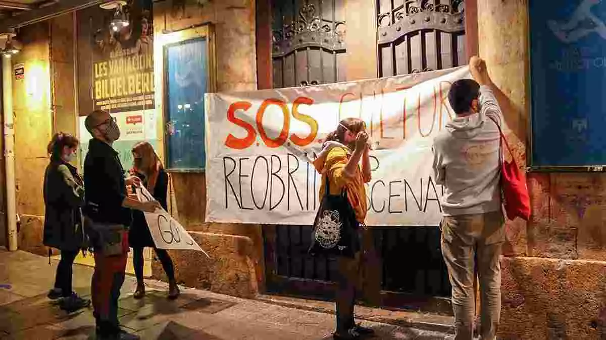 Pla general d'un grup de manifestants penjant una de les pancartes reivindicatives a les portes del Teatre Metropol.