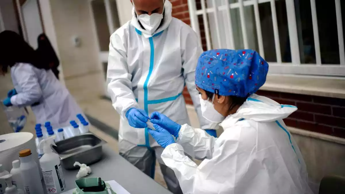 Imatge de dos professionals sanitaris preparant una prova PCR