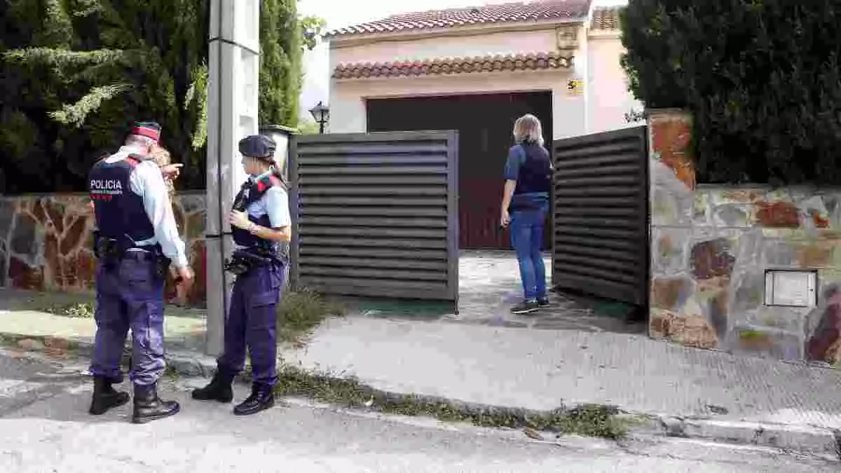 Imatge d'una casa amb dos Mossos parlant a la porta