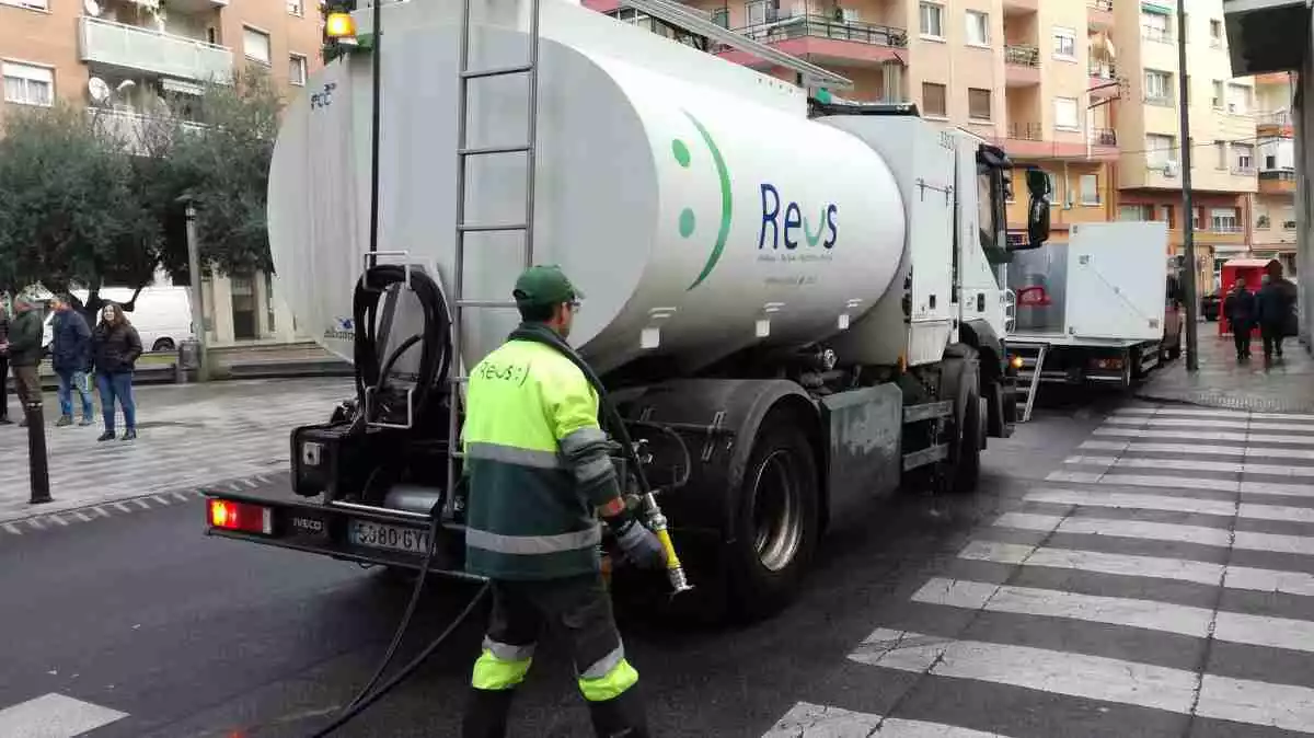 Un camió cisterna del servei de neteja viària de Reus amb un operari subjectant-ne la mànega