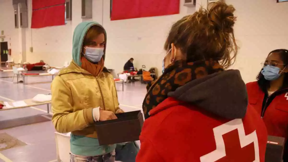 Una dona sense sostre rebent un dels barrets fets per les àvies del projecte de Creu Roja Tarragona