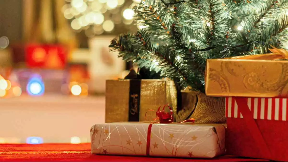 Imatge de tres regals embolicats al costat d'un arbre de Nadal