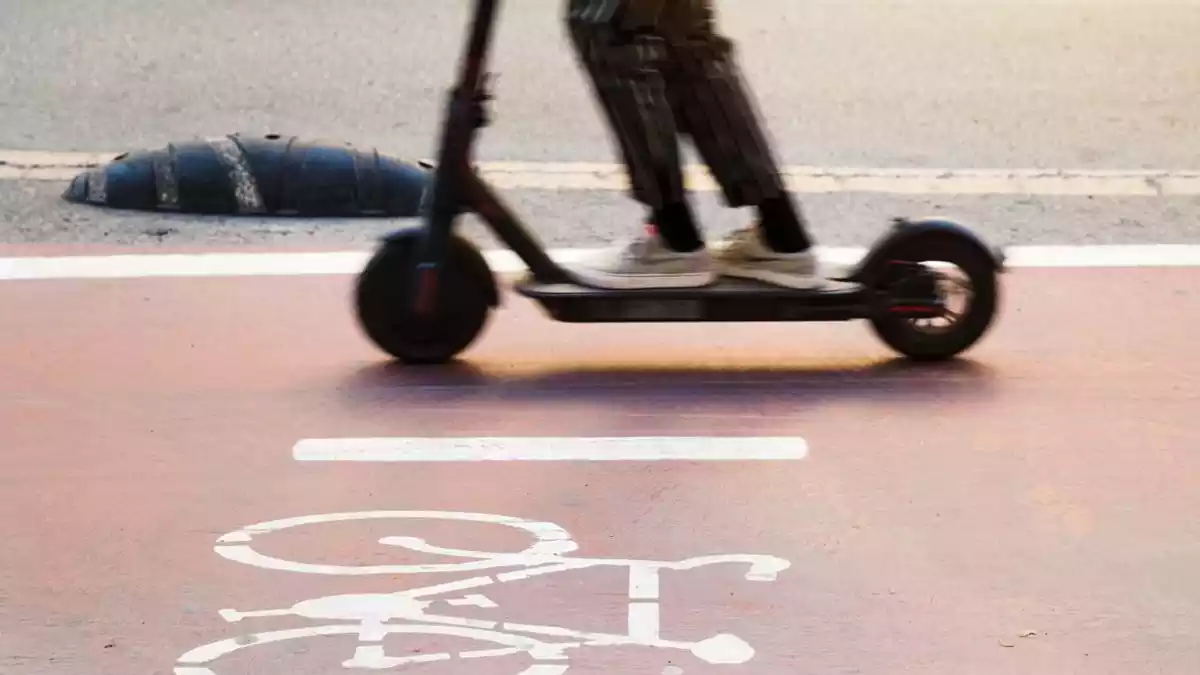 Pla tancat d'un patinet elèctric circulant en un carril bici amb el símbol d'una bici dibuixat