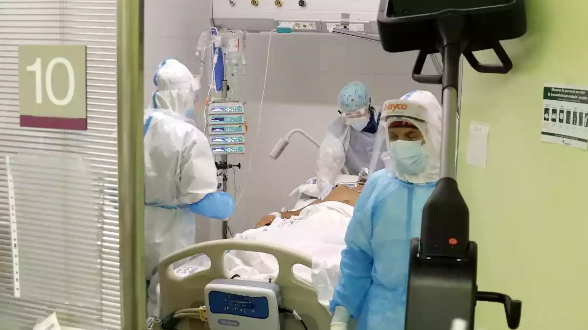 Un pacient amb covid-19 rep atenció a un box d'una UCI en un hospital català