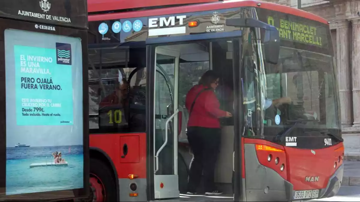 Imatge d'un autobús de l'EMT amb la porta oberta i una persona pujada i pagant a l'entrada.