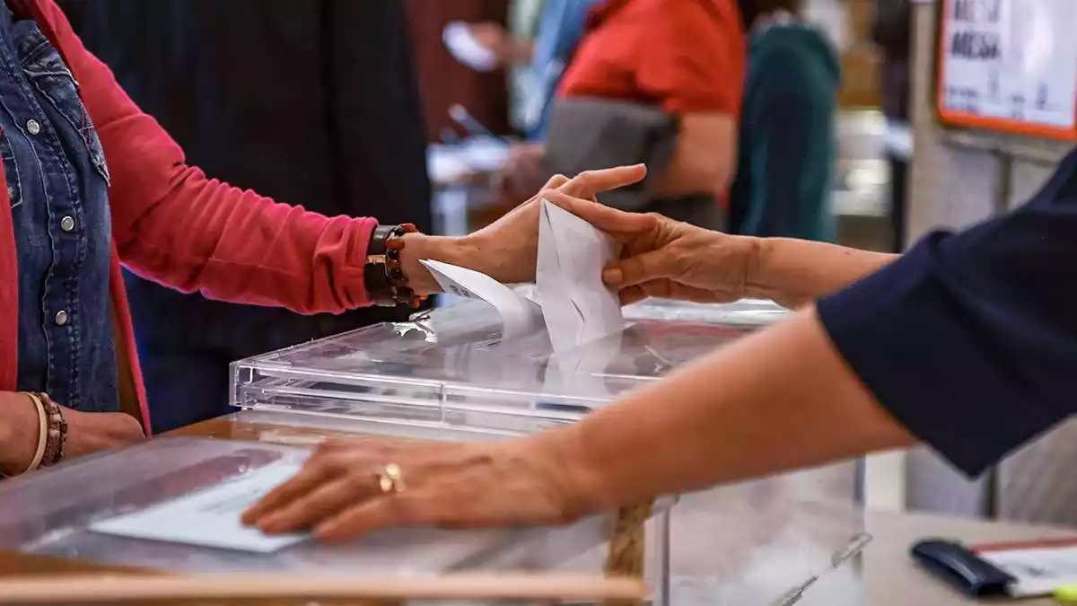 Imatge d'una persona introduint el seu vot dins d'una urna electoral