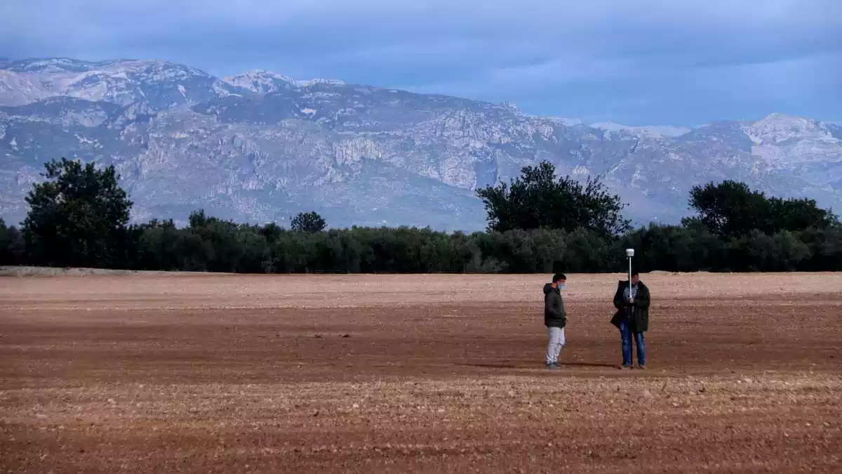 Pla general dels terrenys on es projecta la planta de compostatge a Santa Bàrbara amb dos persones prenent mesures del terreny