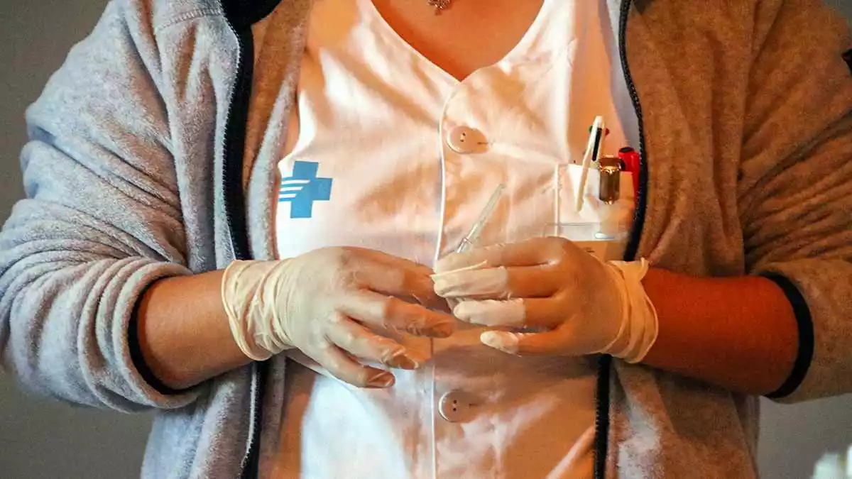 Primer pla d'una infermera amb una vacuna d'AstraZeneca preparada per ser administrada al punt de vacunació del Casal de Roquetes
