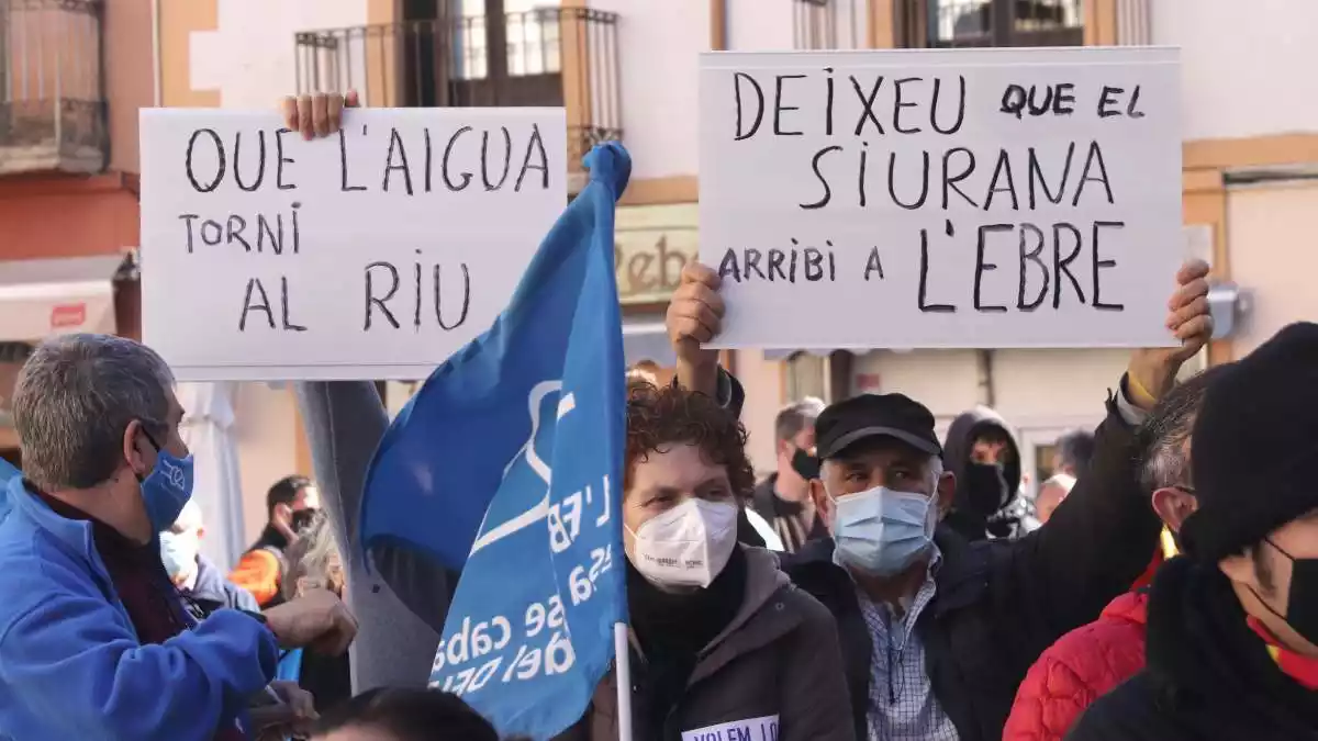 Dos cartells reivindicatius en la concentració de suport als activistes de la Plataforma Riu Siurana