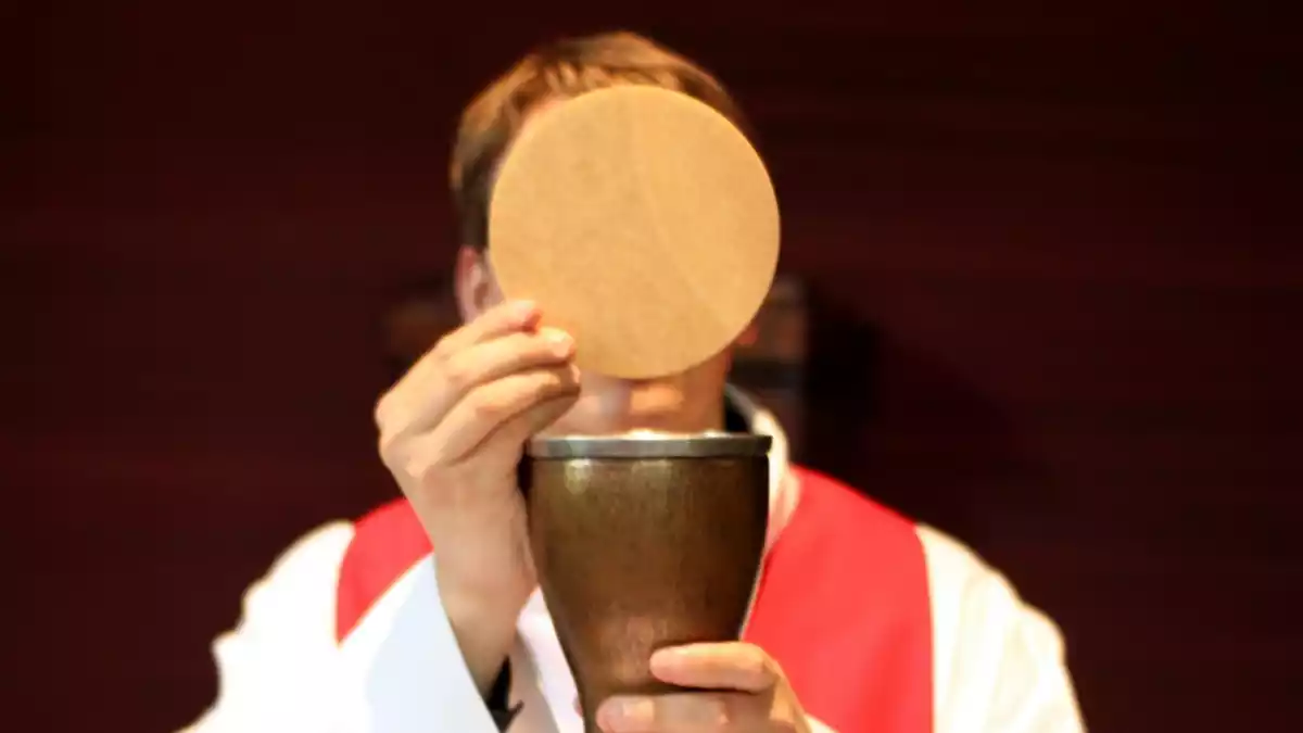 Imatge d'arxiu d'un mossèn amb el calze i l'hòstia, durant una eucaristia