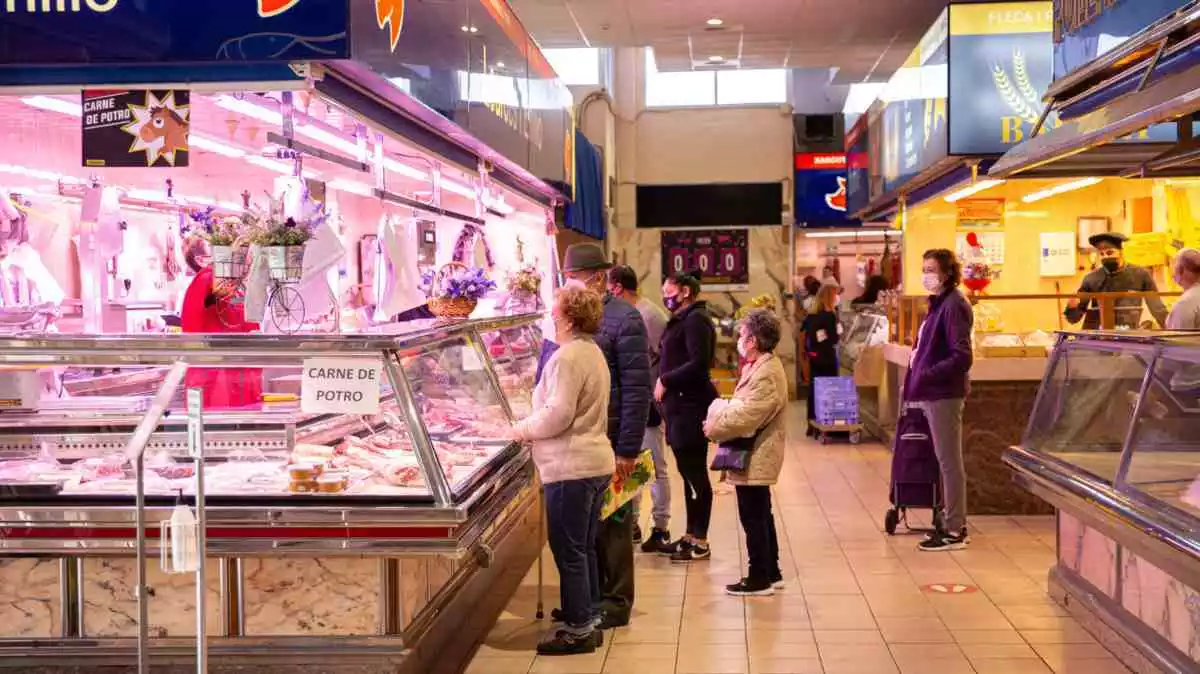Imatge de diverses persones fent cua per comprar en una parada del Mercat de Torreforta de Tarragona