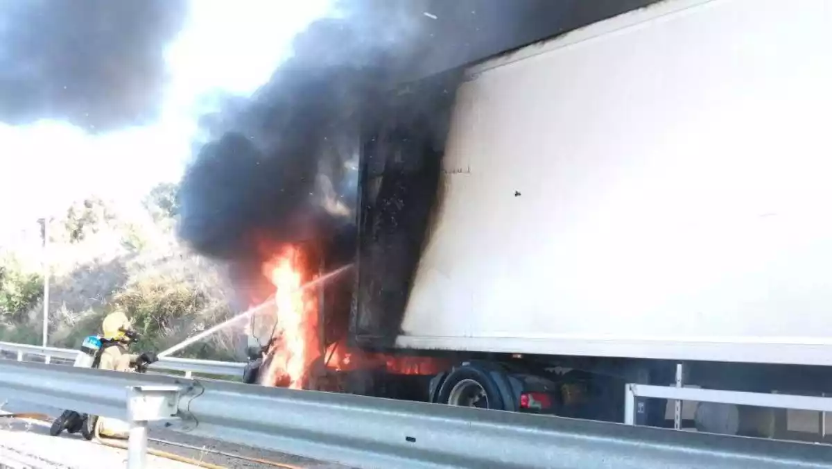 Imatge d'un bomber duent a terme les tasques d'extinció del camió incendiat a l'AP-7 a Tarragona