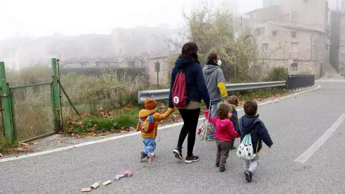 L'educadora i els infants de l'espai familiar d'autogestionat de La Muntanya d'Arbolí caminat pel poble d'esquenes