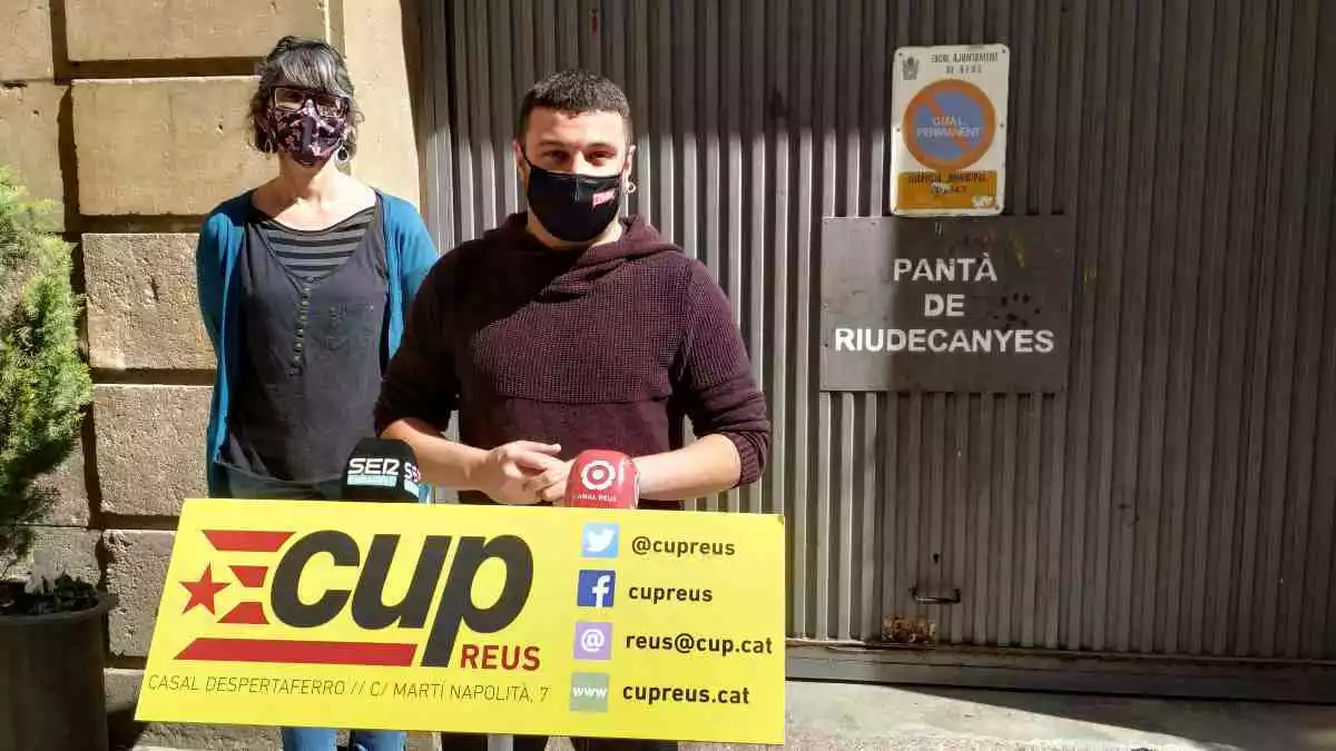 Marta Llorens i Edgar Fernández, amb un faristol de la CUP, davant de les instal·lacions de la Comunitat de Regants del Pantà de Riudecanyes