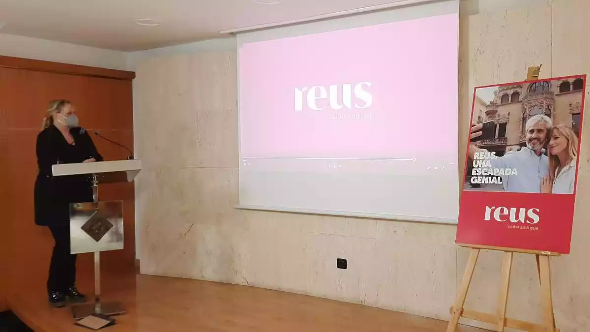 Montserrat Caelles a la sala de premsa de l'Ajuntament de Reus, al costat d'un projector i un cartell de la campanya