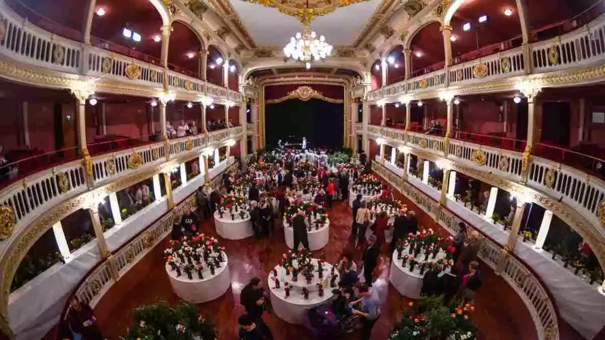 La platea del Teatre Bartrina plena de taules amb roses exposades i públic passant a mirar-se-les