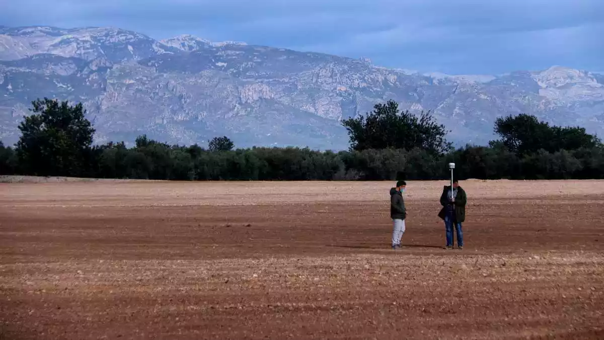 Terrenys on es projecta la planta de compostatge a Santa Bàrbara amb dos persones prenent mesures