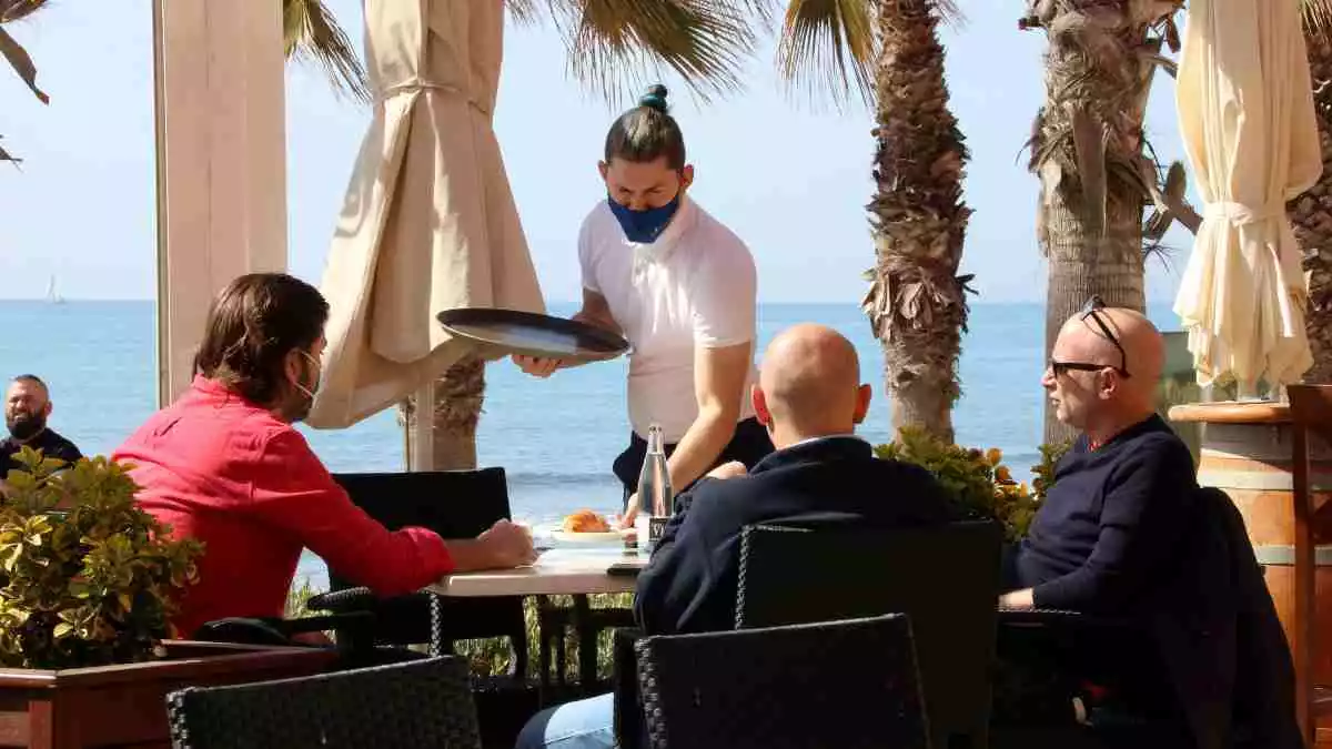 Imatge d'un cambrer servint una taula en una terrassa de Sitges